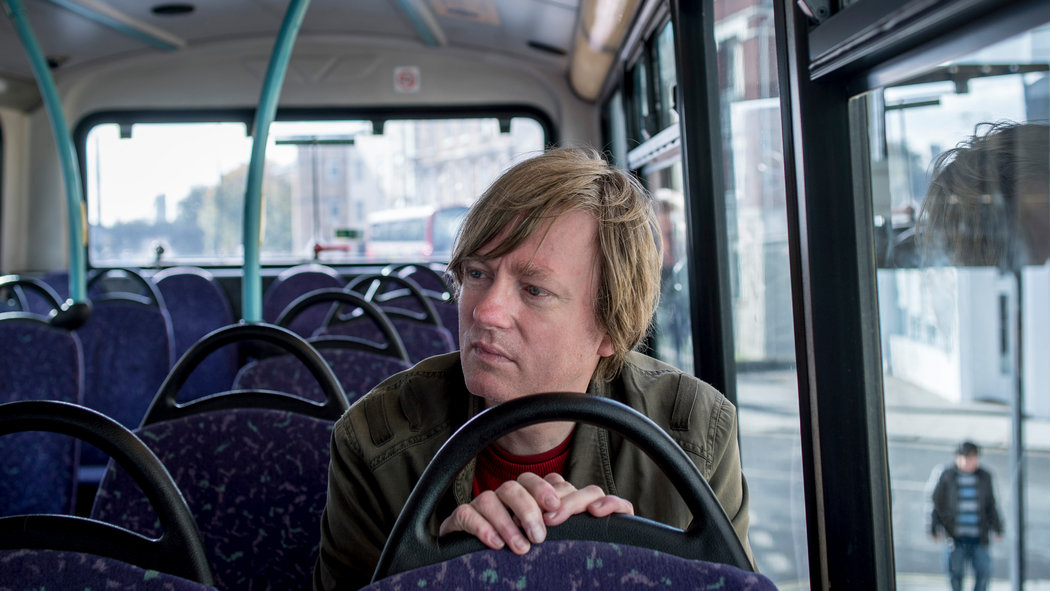 Michel Faber sits on (what looks like) a Lothian Bus in Edinburgh