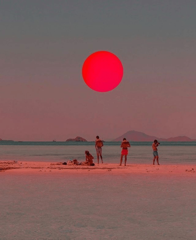 A deep red sun on an eerie looking beach